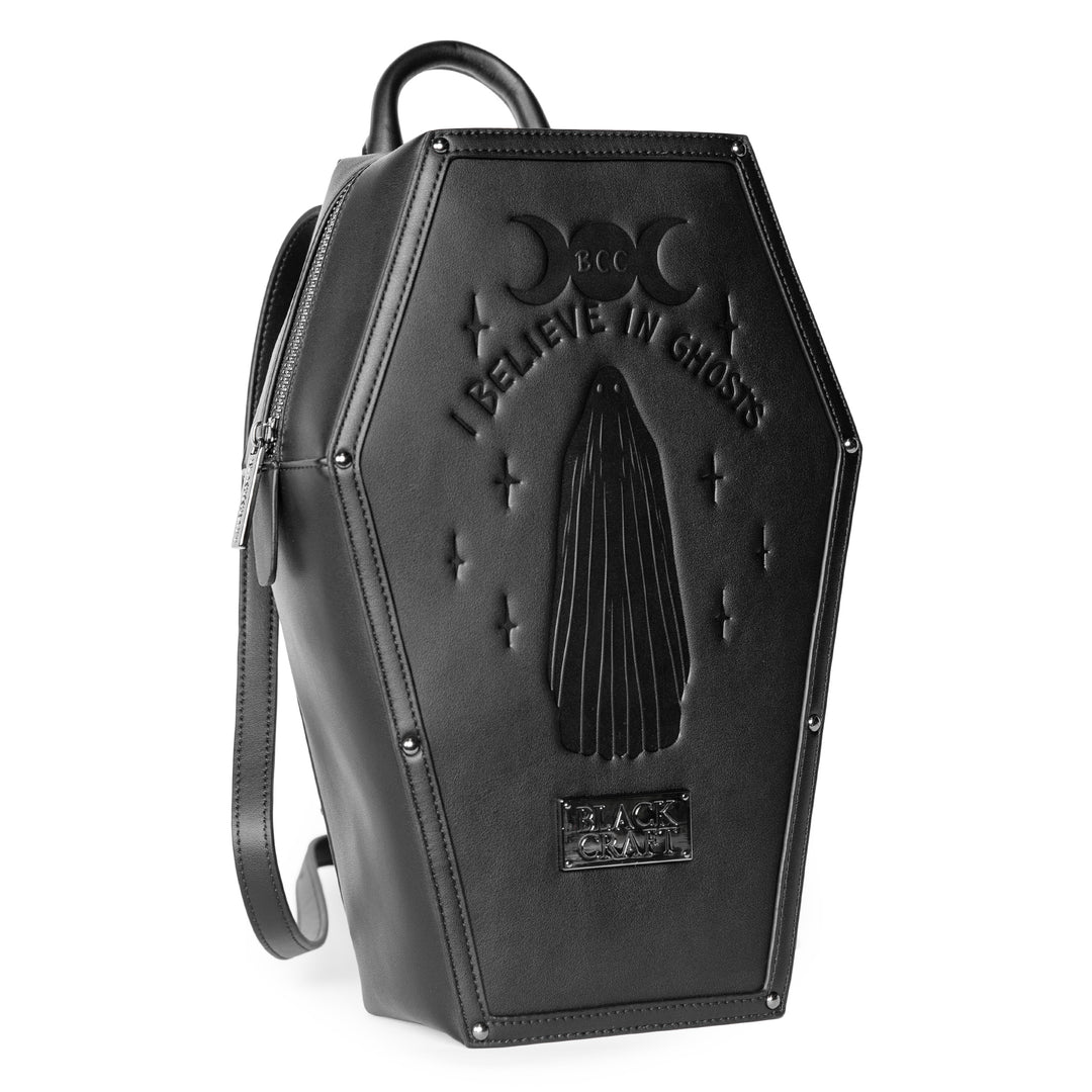 Black faux leather coffin shaped backpack with I Believe in Ghosts Stories art embossed on front.