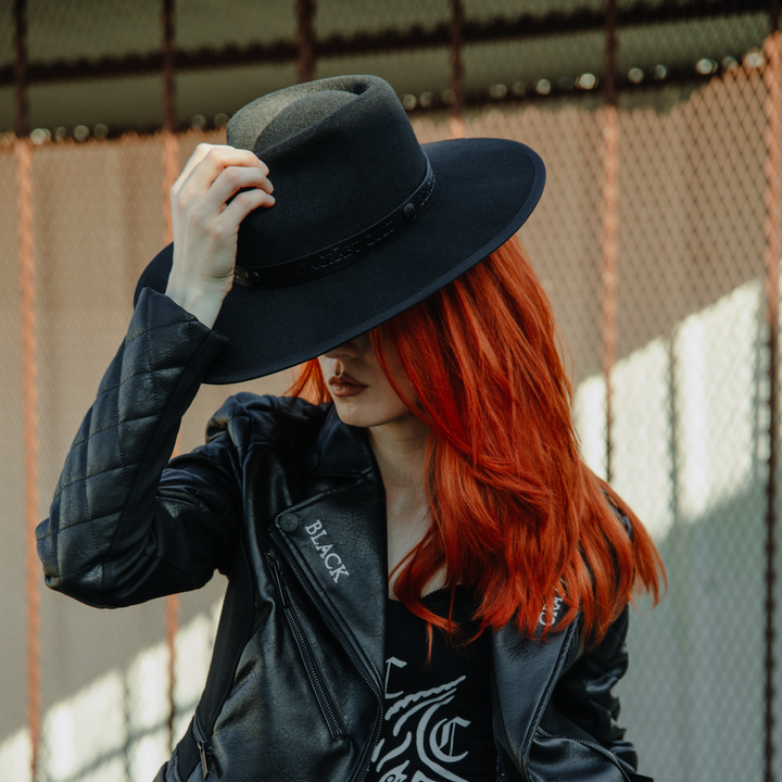 A model wearing a black wide brimmed fedora hat.