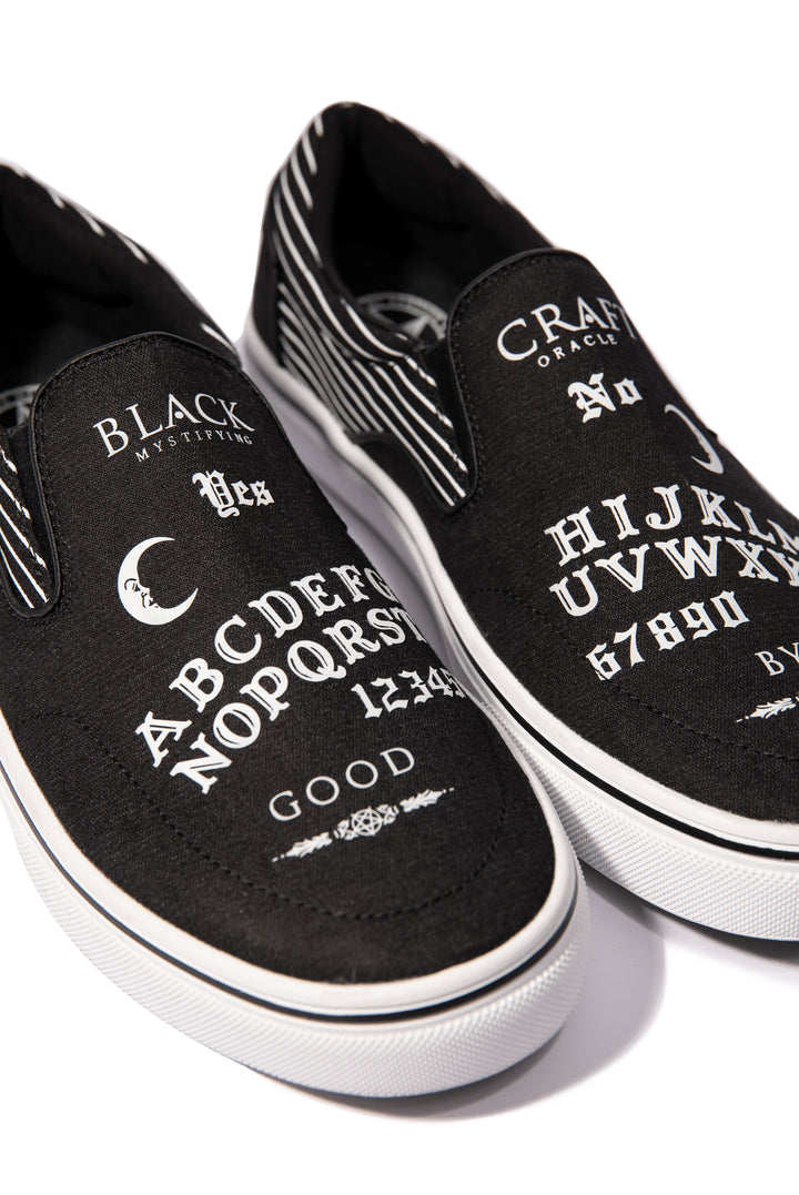 A slip on sneaker featuring our signature Ouija artwork on black canvas fabric upper and custom Blackcraft logo rubber sole.